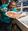 A Belizean restaurant employee is displaying a plate of fresh fish.