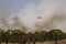 Bell 412 helicopter flying against plumes of smoke while fighting bush fires.