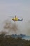 Bell 412 helicopter flying against plumes of smoke while fighting bush fires.