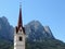 Bell tower of the Church of St Maria Ausiliatrice against the Dolomites . Siusi allo Sciliar, South Tyrol, Italy