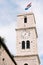 Bell tower with the clock of the Church of St. John in Sibenik against the blue sky