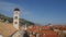 The bell tower of the Franciscan monastery in Dubrovnik against the background of the roofs of the city in the tiles.