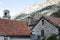 The bell tower stands tall amidst the historic stone buildings and terracotta roofs of Kotor, with the ancient fortifications