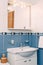 Bellagio, Italy - 07 june 2020: The bathroom is blue with a washbasin, a mirror and lights above it.
