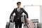 Bellboy holding many suitcases and standing in front of a luggage cart