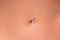 Belly piercing in the navel close up