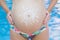 Belly of pregnant girl over swimming pool