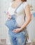 Belly of a pregnant woman in a denim overalls