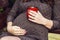 Belly of pregnant woman sitting on a swing, with a cup of tea. pregnant woman relaxing in the park.