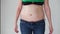 Belly and sides protruding from the female jeans before and after losing weight.