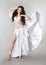 Bellydance. Beautiful belly dancer woman in white shining costume with blowing fabric. Long healthy curly hair. arabian