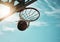 Below, basketball and net with sky in summer for shooting, scoring and points to win game. Hoop, rim and ball in closeup