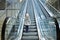 From below shot of girl standing on moving stairs in terminal.