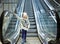 From below shot of girl standing on moving stairs in terminal.