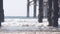 Below wooden Crystal pier on piles, ocean beach water waves, California USA.