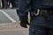 Belt of a policeman in black uniform in action, with handcuffs, baton and belt bag