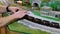 Bemidji, MN - 14 May 2016: man adds an additional toy train car to model railroad.