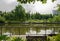 Bench at fenced and planked riverside in verdant city of cloudy