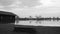 Bench filled with stones behind grids on small shore at lake constance after sunset in black and white