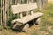 Bench, made of wood is in front of a wooden fence in countryside