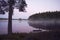 Bench by misty lake in beautiful sunrise.