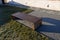 A bench of one piece of sheet metal in a regular garden with a stone walkway of gray flat slate. low wall with gray recessed light