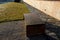 A bench of one piece of sheet metal in a regular garden with a stone walkway of gray flat slate. low wall with gray recessed light