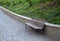 Bench at a retaining wall in a park of black bushes early spring perennials on a high flowerbed path of granite cubes