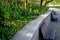 Bench at a retaining wall in a park of black bushes early spring perennials on a high flowerbed path of granite cubes