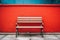 a bench sitting in front of a red wall