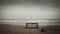 a bench sitting on top of a sandy beach next to the ocean on a cloudy day with a person walking in the distance in the distance