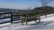 Bench in snow by fence