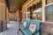 Benches against front windows at open porch of house with stone exterior wall