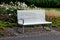 Benches with metallic shiny stainless steel construction, armrests, white wood paneling in public parks. under a bench of granite