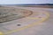 Bend in airport taxiway. Yellow markings, day, no people