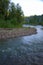 The bend of a mountain river flowing through a forest with rocky shores