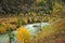 A bend of a turbulent mountain river of turquoise color, flowing through an autumn valley at the foot of high mountains