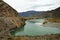 A bend of a wide turquoise river flowing through an autumnal valley along high mountains