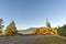 Bending asphalted road between green bushes and red tree, blue s