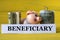 BENEFICIARY - word on a white strip of paper on a piggy bank pig on a yellow background with banknotes