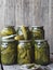 The benefits and harms of canned pickled cucumbers. Pickled cucumbers on a fork and in cans on a wooden ancient background. Side