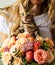 Bengal kitten sitting bouquet of flowers by faceless woman