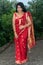 A Bengali girl wearing the red sari and golden ornaments giving poses on the roof of the forest bungalow