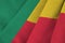 Benin flag with big folds waving close up under the studio light indoors. The official symbols and colors in banner