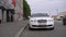 Bentley white luxury car. Front bumper, headlights, grill. Auto in a city.