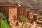 Berber village in valley surrounded by rugged high mountain walls with old brick clay houses