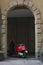 Bergamo, Italy - 24.6.2019: Red city scooter Vespa parked in round wall recess. Traditional, vintage Italian moped.