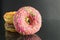 Berliner doughnuts with icing pink yellow lie stops and pink bright stands on a black background with room for text