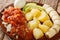 Bermuda codfish breakfast with onion tomato sauce, boiled potatoes, eggs, banana and avocado close-up in a plate. horizontal