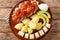 Bermuda codfish breakfast with onion tomato sauce, boiled potatoes, eggs, banana and avocado close-up in a plate. horizontal top